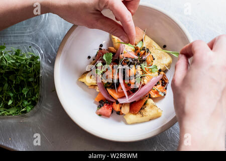 Hohen Winkel in der Nähe der Person garnieren Platte von Lebensmitteln mit einigen Kräutern. Stockfoto