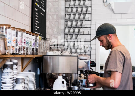 Ein Mann barista Arbeiten eine Kaffeemaschine in einem Café. Stockfoto