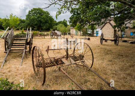 Alte Kutschen und Tools stehen auf einer trockenen Wiese in St. Lyphard Stockfoto