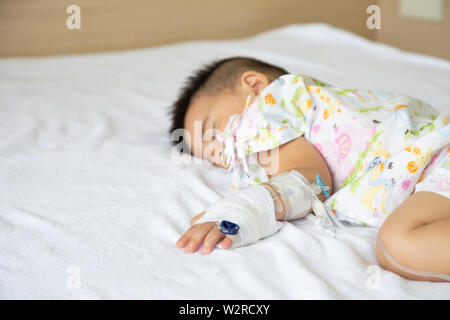 Asiatische Baby schlafend auf dem Bett mit Infusion mit Kind Abteilung im Krankenhaus. Kinder mit ansteckenden Krankheiten IPD, Invasive Pneumococcal Dis Stockfoto