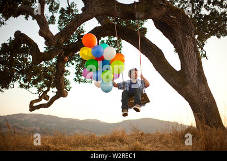 Junge auf Schwingen grosse Bündel Luftballons. Stockfoto