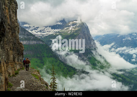 Wanderer, von hinten gesehen, wandern die Highline Trail in Richtung Logan Pass, Glacier National Park, Montana, nördlichen Rocky Mountains, USA. Stockfoto