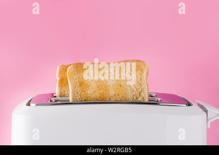 Getoastetes Toast Brot im Toaster weiß auf rosa Hintergrund Stockfoto