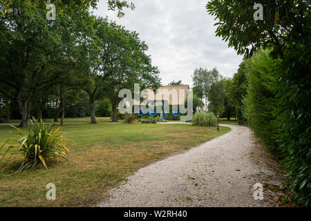 Kleine Straße, die zu einem alten Haus mit Strohdach Stockfoto