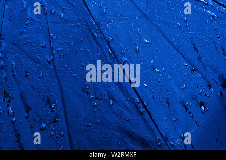 Wet Blue Regenschirm Nahaufnahme Bild. Wasserdichtes Gewebe Tuch mit Wasser Tropfen und Spritzer. Gutes oder Schlechtes Wetter Konzept. Regen in vier Jahreszeiten. Schutz Stockfoto