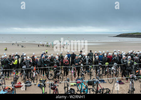 Unter dunklen Wolken, die Wettbewerber im Jahr 2019 Barry Island sprint Triathlon warten auf der Promenade neben dem Strand von ihrer Rasse zu starten. Stockfoto