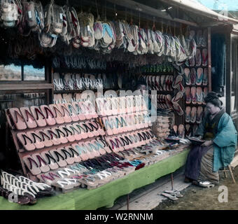 [1890s Japan - Geta schuhe Shop] - ein Geschäft mit Geta, Japanisch Holzschuh Verschleiß, Ca. In den 1880ern. Die Wurzeln der geta Zurück zur yayoi Ära, aber sie wurde besonders populär in der Edo Periode (1600 - 1868). Geta Handwerker angeboten eine Vielzahl von Geta, abhängig von der Mode der Zeit. 19 Vintage Glas schieben. Stockfoto