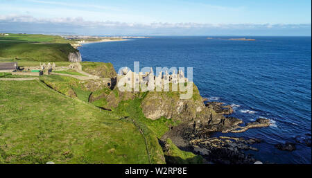 Die Ruinen der mittelalterlichen Dunluce Castle auf einem steilen Felsen in der Nähe von Folkestone. Der nördlichen Küste des County Antrim, Nordirland, Großbritannien. Luftaufnahme im Sonnenaufgang. Stockfoto