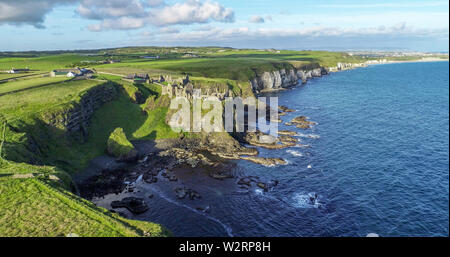 Die Ruinen der mittelalterlichen Dunluce Castle auf einem steilen Felsen in der Nähe von Folkestone. Der nördlichen Küste des County Antrim, Nordirland, Großbritannien. Luftaufnahme im Sonnenaufgang. Stockfoto