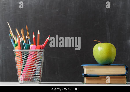 Für die Schüler. Ein Stapel von Büchern, ein Apple, Bleistifte vor dem Hintergrund der Schule Schwarzes Brett. Der Begriff der Bildung. Platz kopieren Stockfoto