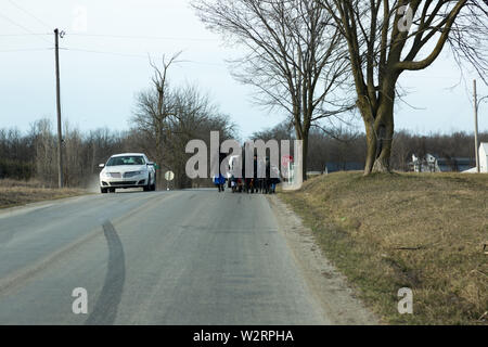 Ein Amish Familie Spaziergänge entlang einer Landstraße an einem kalten Wintertag in der Nähe von Spencerville, Indiana, USA. Stockfoto