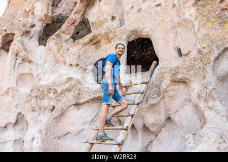 Mann Tourist gerne klettern Leiter auf Main Loop Trail Pfad im Bandelier National Monument in New Mexico im Sommer durch Canyon Cliff Stockfoto