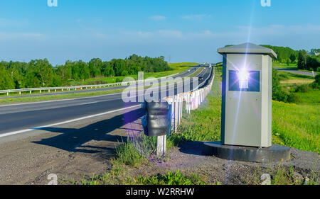 Rückfahrkamera zur Festsetzung der Bewegung von Autos aus Beschleunigung, die auf einer Landstraße im Sommer steht auf dem Hintergrund der vorbeifahrenden Autos Stockfoto