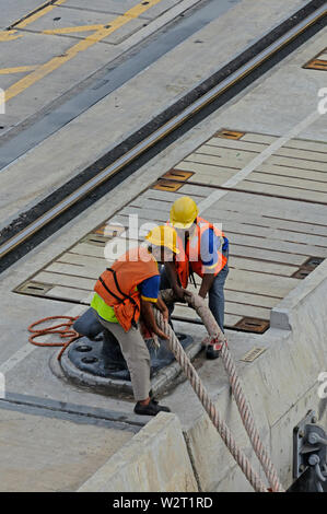 Port Klang, Selangor Westport/Malaysia - Dezember 27, 2014: Zwei Hafenarbeiter Abbau Linien der scheidende großes Containerschiff vom Kai Poller Stockfoto