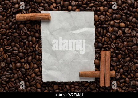 Weißes leeres Blatt Papier auf dem Hintergrund von gerösteten Kaffeebohnen und Zimt für Text Menü oder Rezept Stockfoto