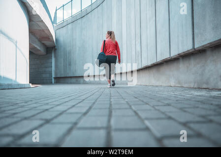 Training ist vorbei. Rückansicht des Plus size Frau in Sport Kleidung tragen ihre Tasche und nach Hause nach Übungen im Freien. Sport Konzept. Fettsäuren Frauen Stockfoto