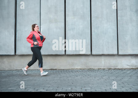 Alles ist möglich. Junge Frau in Sport Plus size Kleidung laufen im Freien. Gesunde Lebensweise. Gewicht zu verlieren. Sport Konzept Stockfoto