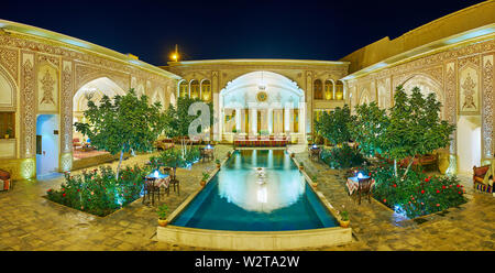 KASHAN, IRAN - Oktober 23, 2017: Panorama der Abend Mahinestan Raheb historisches Haus mit hellen Beleuchtung, kleinen Brunnen, grünen Garten und Orna Stockfoto