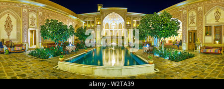 KASHAN, IRAN - Oktober 23, 2017: Panorama der Abend Mahinestan Raheb historisches Haus mit einem kleinen Garten, reich verzierte Gebäude, Sommerterrasse und Brunnen Stockfoto