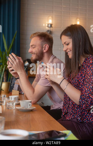 Zwei Freunde sitzen zusammen in einem Cafe, mit Smart-phones. sitzen zusammen, doch jeder an Ihrem Telefon. Stockfoto