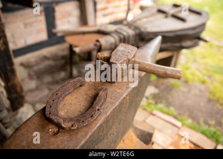 Werkzeuge in der Werkstatt eines alten Schmied. Hufeisen und Hammer auf einem Amboss. Platz - Open-air Museum. Stockfoto