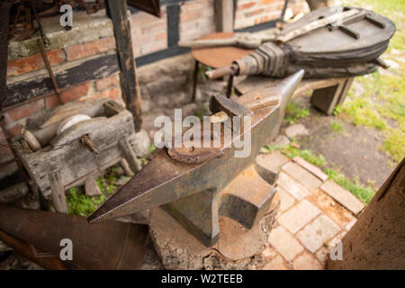 Werkzeuge in der Werkstatt eines alten Schmied. Hufeisen und Hammer auf einem Amboss. Platz - Open-air Museum. Stockfoto