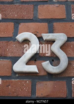 Haus Nummer 23, weiße Zahlen auf einem Klinker Wand Stockfoto