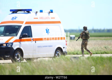 Buzau, Rumänien - 22. Mai 2019: Die rumänische Armee Soldat Patrouillen ein Military Air Base, in der Nähe von einem Krankenwagen, während einer Räumungsübung. Stockfoto