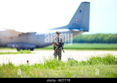 Boboc, Rumänien - 22. Mai 2019: Die rumänische Armee Soldat Patrouillen ein Military Air Base, mit einem Alenia C-27J Spartan militärischen Frachtflugzeug aus der Bulgarischen Stockfoto