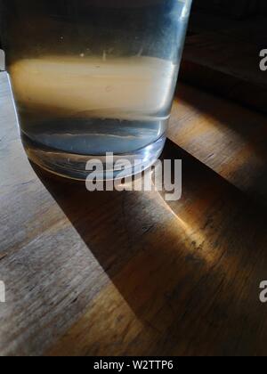 Flasche Trinkwasser auf Holztisch im Abendlicht Stockfoto