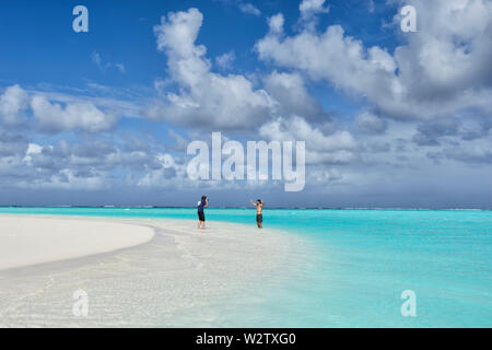 Touristische posieren für ein Foto auf einem weißen Sandstrand an der türkisfarbenen Lagune von Aitutaki, Cook Inseln, Polynesien Stockfoto