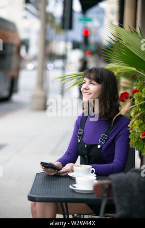 Frau eine Pause in einem Café oder lokalen Cafe in der Stadt und warten, um einen Freund zu treffen. Sie sitzen in einem Straßencafé Restaurant h Stockfoto