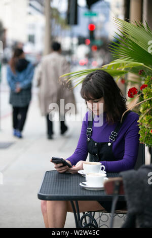Frau eine Pause in einem Café oder lokalen Cafe in der Stadt und warten, um einen Freund zu treffen. Sie sitzen in einem Straßencafé Restaurant h Stockfoto