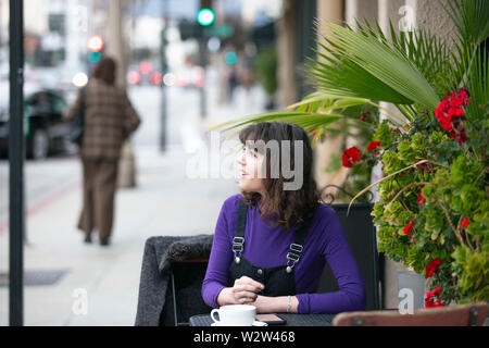 Frau eine Pause in einem Café oder lokalen Cafe in der Stadt und warten, um einen Freund zu treffen. Sie sitzen in einem Straßencafé Restaurant h Stockfoto
