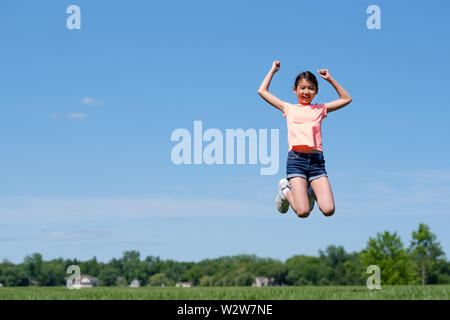 Gerne Asiatische jugendlich Mädchen springt hoch in die Luft Stockfoto