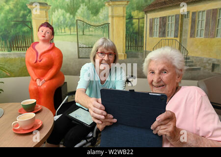 Kassel, Deutschland. 26 Juni, 2019. Rosemarie Fischer (l, 81) und Gisela Bossecker (95) Foto die Reporter mit einem Tablett in der Käthe-Richter-Haus Seniorenheim. In Altersheimen, das Internet war ein Nischendasein. Aber Pflegeheime Umdenken - auch, weil ihre Klientel verändert sich. Quelle: Uwe Zucchi/dpa/Alamy leben Nachrichten Stockfoto