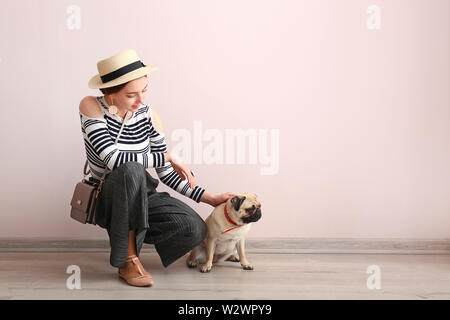 Junges Mädchen mit niedlichen Mops Hund in der Nähe von Farbe Wand Stockfoto