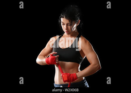 Sportliche weiblichen Boxer Anwendung Armbänder gegen den dunklen Hintergrund Stockfoto