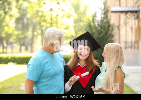 Glückliche junge Frau, die mit ihren Eltern am Tag der Promotion Stockfoto