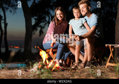 Familie braten Würstchen über dem Lagerfeuer am Abend Stockfoto