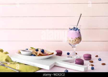 Leckere Desserts mit Heidelbeeren und Joghurt im Glas auf weißen Tisch Stockfoto