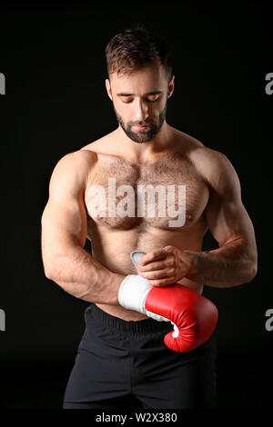 Starke männliche Boxer auf Handschuhe gegen den dunklen Hintergrund Stockfoto