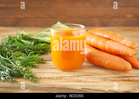Glas leckeren Karottensaft auf hölzernen Tisch Stockfoto