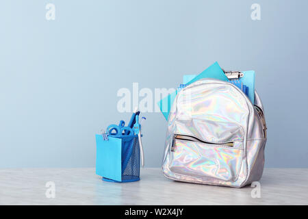 Schule Rucksack und Schreibwaren auf Tisch gegen Farbe Hintergrund Stockfoto