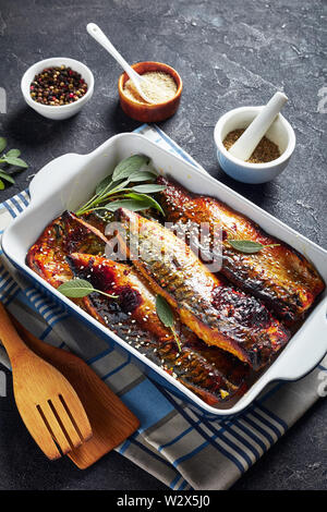 Köstliche gegrillte Filets von Makrele Fisch in einer Auflaufform auf einer konkreten Tabelle mit Gewürzen im Hintergrund, vertikale Ansicht von oben Stockfoto