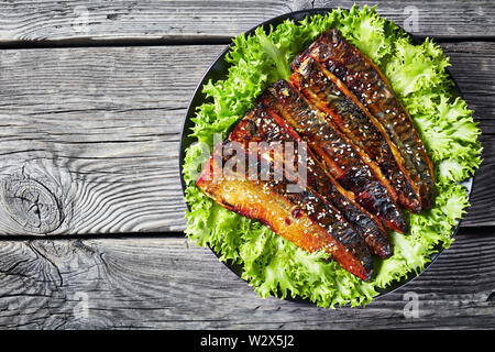Gebratene Filets von Makrele Fisch mit Salat auf einem weißen Teller auf einem rustikalen Holztisch, Ansicht von oben, flatlay, leeren Raum Stockfoto