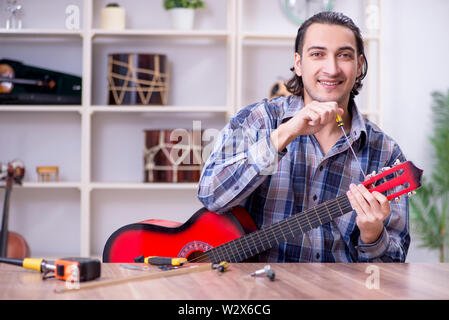 Die junge schöne Handwerker Reparatur Gitarre Stockfoto