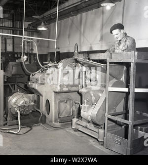 1950, historische, männliche und weibliche Arbeitnehmer mit Maschinen innerhalb einer Batterie factory, London, England, UK. Stockfoto