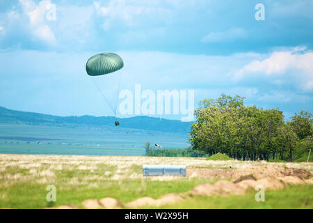 Eine militärische Kiste wird aus einem militärischen Frachtflugzeug während einer Räumungsübung Fallschirm. Stockfoto