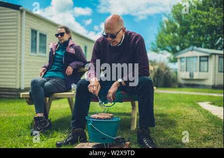 Ein älterer Mann und seine Tochter sind, genießen Sie ein Barbecue im Trailer park Stockfoto